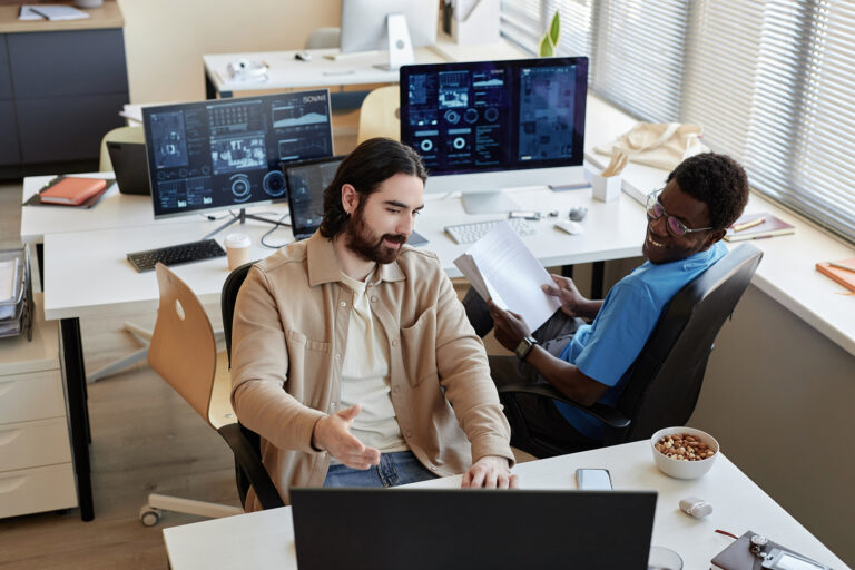 Young businessman showing data on computer screen to colleague